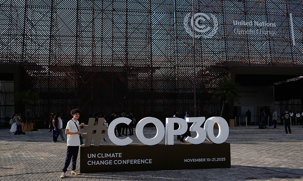 A person poses for a photo with a sign for the COP30 U.N. Climate Summit